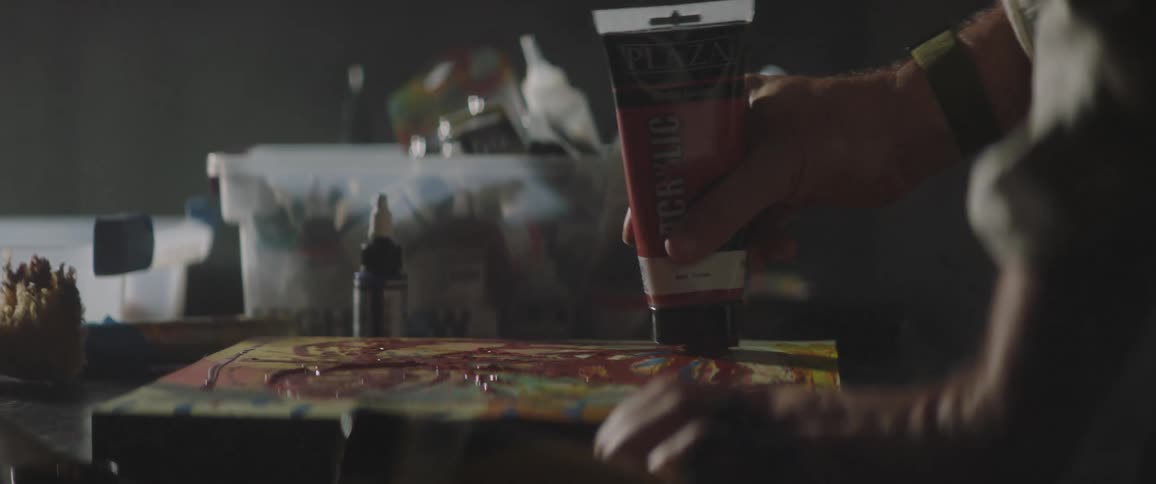 A person in a room putting paint on a canvas on a table
