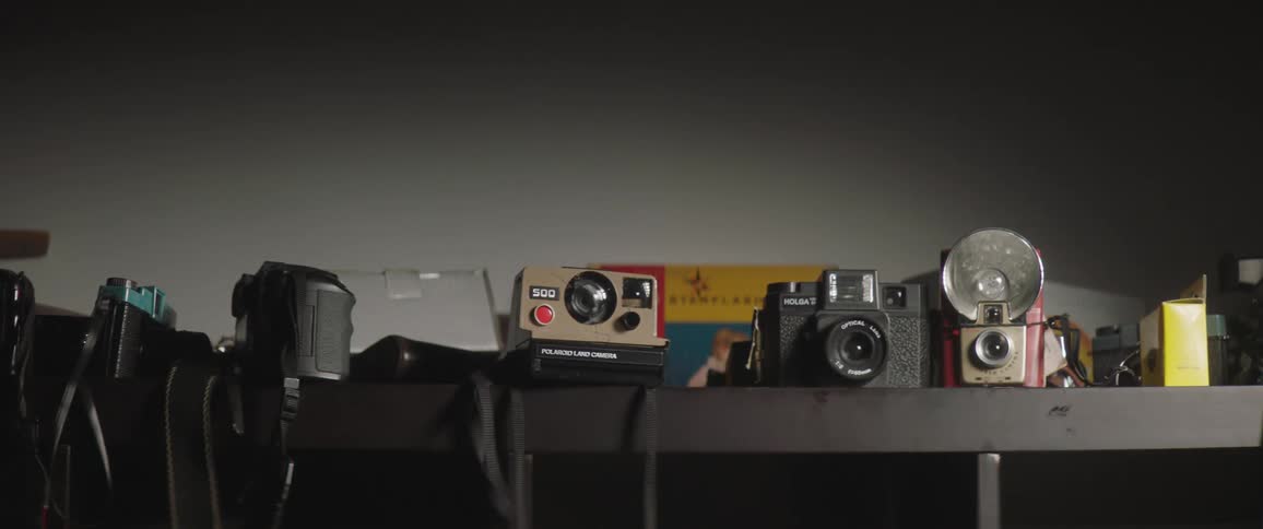Various retro cameras sit on a shelf