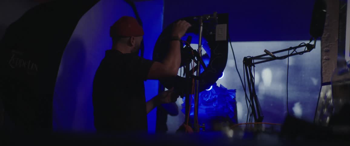A man with a hat in the studio taking a picture of a woman with a camera