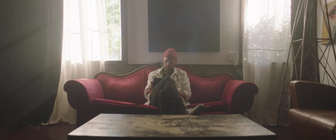 A man is sitting on a couch in his living room during the day