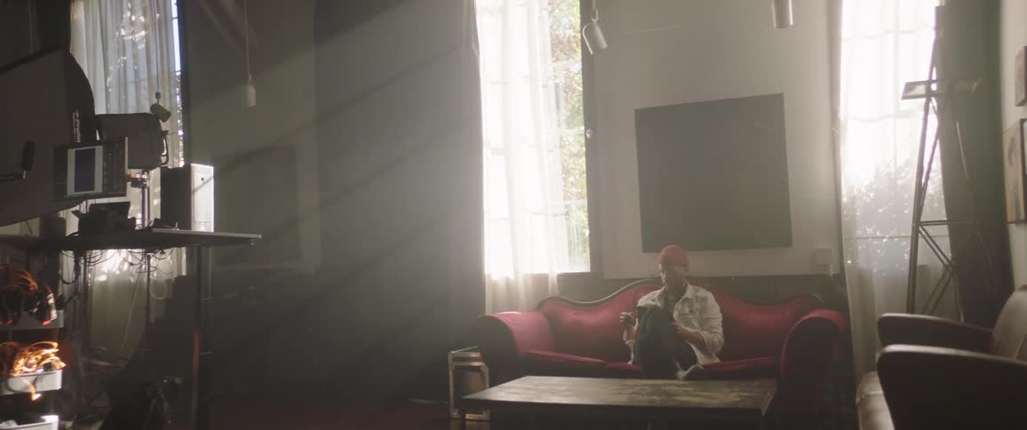 A man is looking at a camera while sitting on the couch