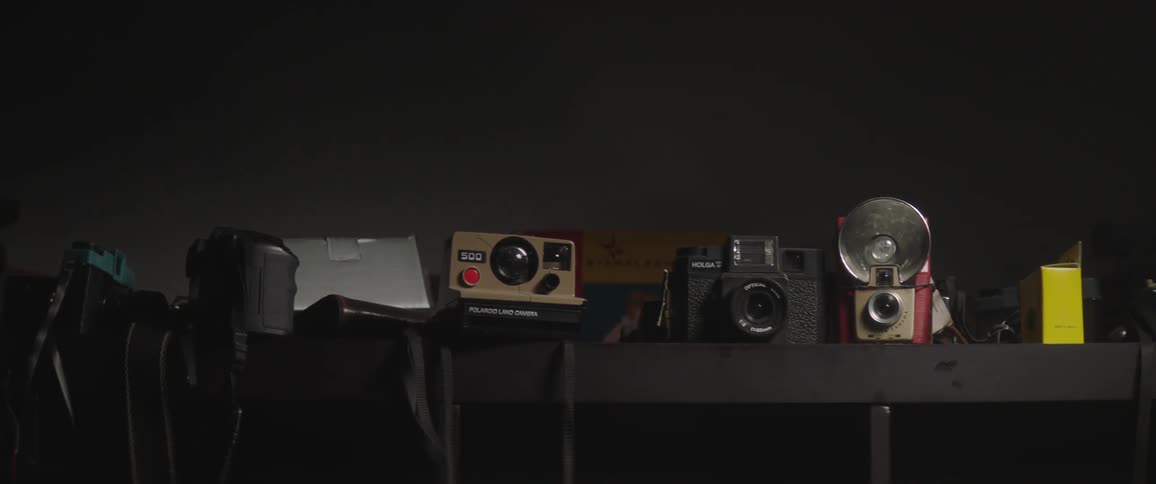 A collection of cameras sitting on shelves