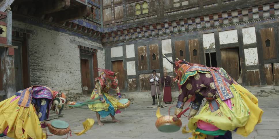 A group of people in costumes dance and wave objects around