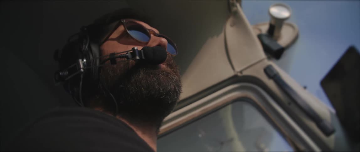 A pilot wearing a headset is looking around inside a plane