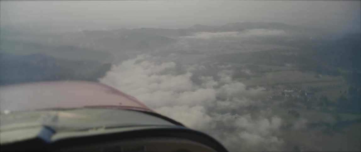 An airplane is flying over clouds on a foggy day