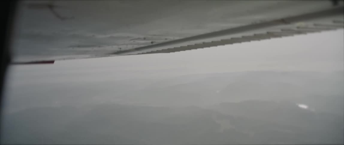 An aircraft flying in the air with a landscape the sky and clouds in the background