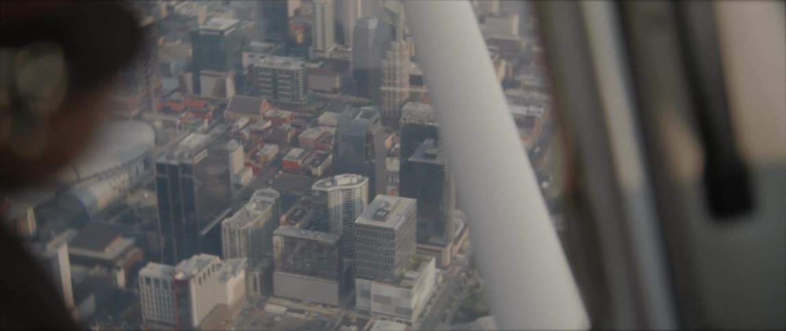 Pilot with beard and mustache flies over mist covered city
