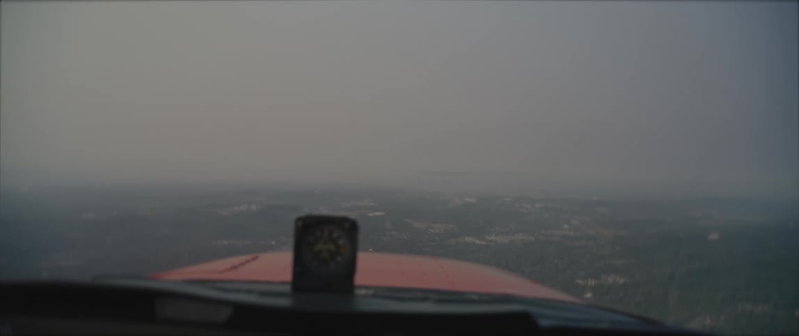 View from the cockpit of a flying airplane over a small town covered in fog