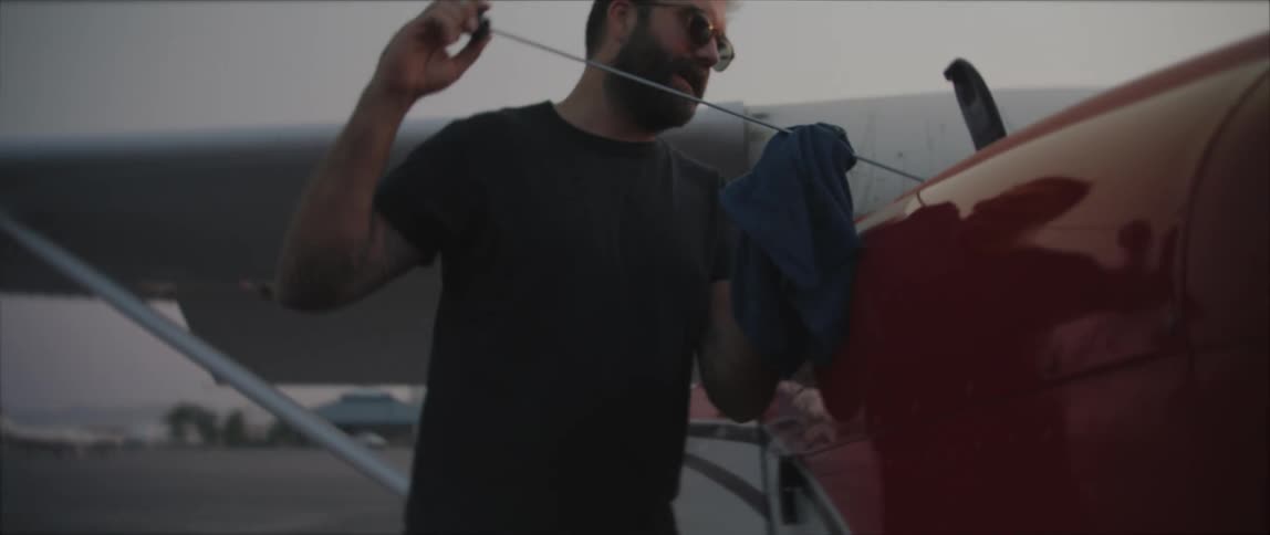 A man uses a rag to check the oil stick of a small airplane