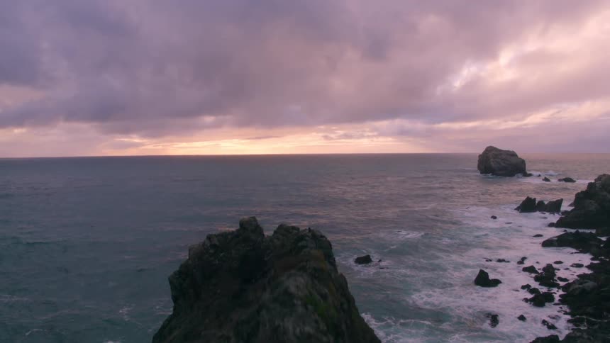 Clouds are hovering over coastal cliffs at dusk