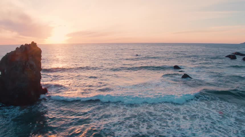 The tide washes into a rocky coastline in the evening