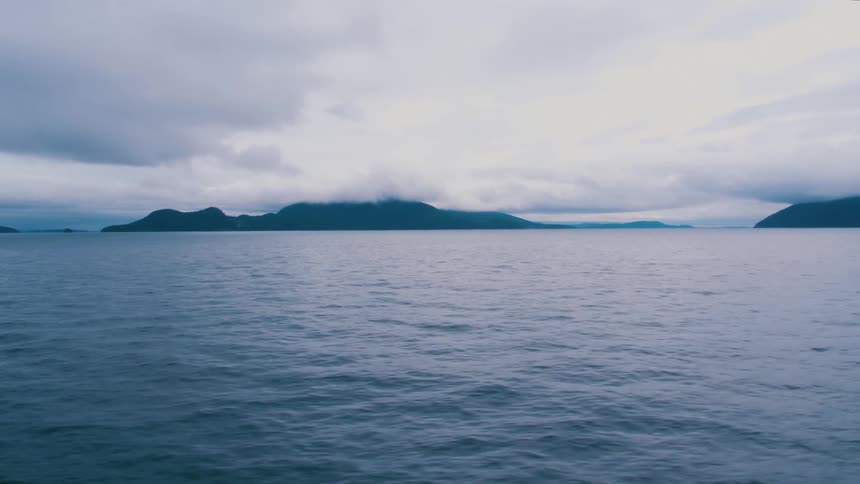 A lake with water with land the sky and clouds in the background