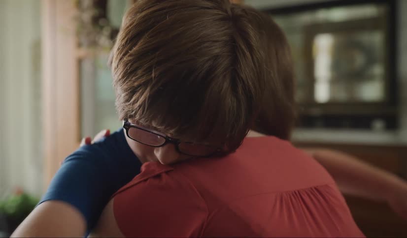 Sad looking young boy walks towards his mother and they hug