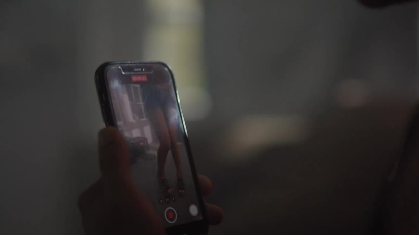 A man is filming a woman dancing on his cell phone