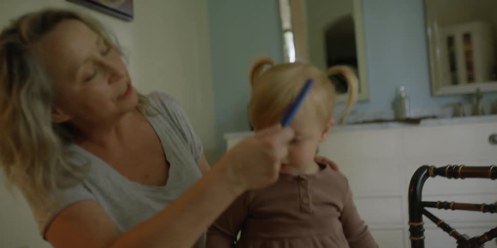 Mother combs daughters hair with blue comb