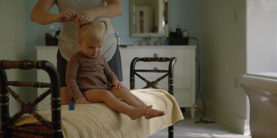 A mother putting her daughters hair in pigtails