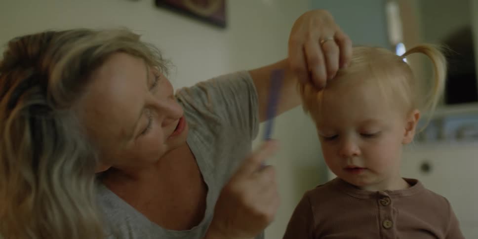 Mother combs her young toddlers bangs