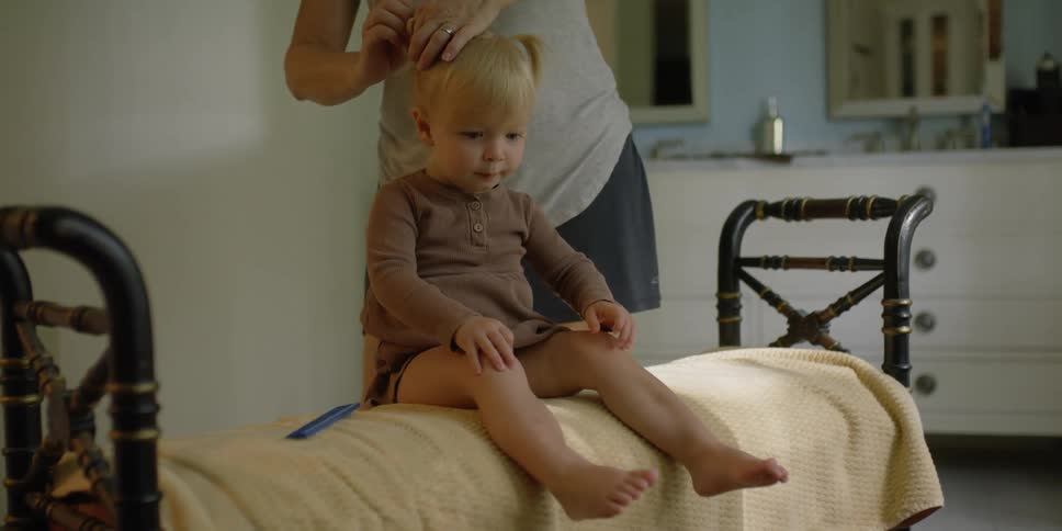 A woman is putting hair ties on a child