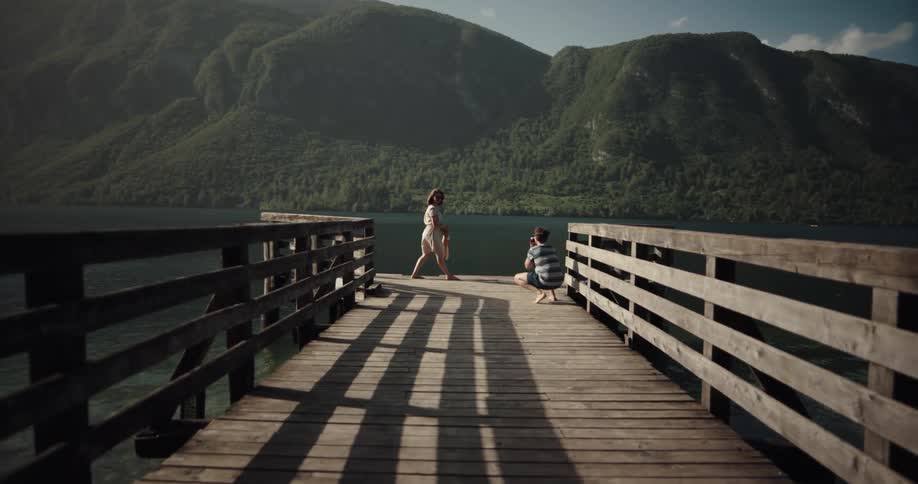 A young woman playfully jumps around and poses for photographs being taken by her male companion