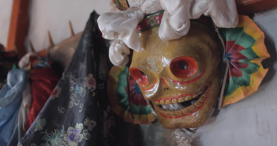 A painted mask with coats hanging next to it
