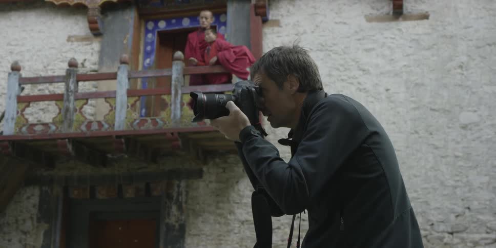 A man is photographing as monks watch on