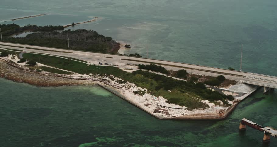 A highway near a coast next to trees and grass with the ocean in the background