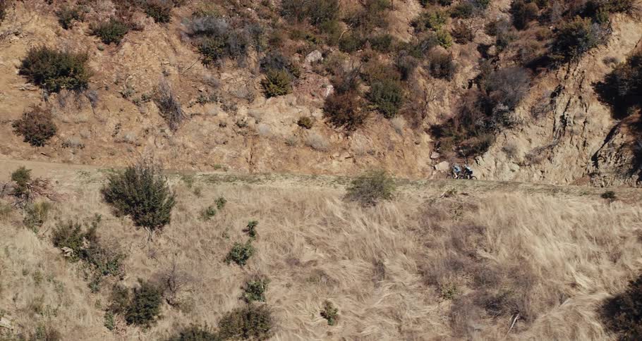 Bicyclists pedal along a narrow road in the hills of a desert