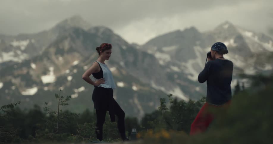 A man is photographing a woman near a mountain range