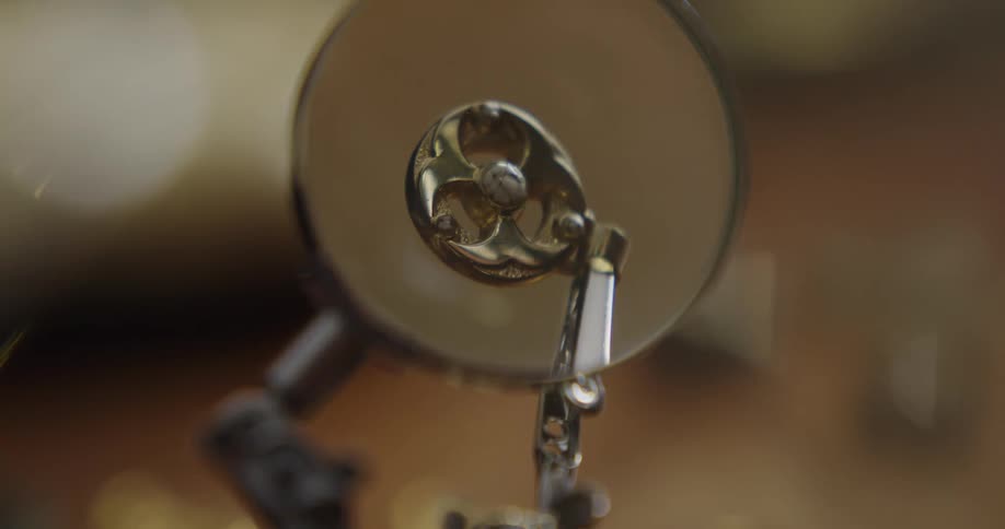 A magnifying glass is put in front of a piece of jewelry