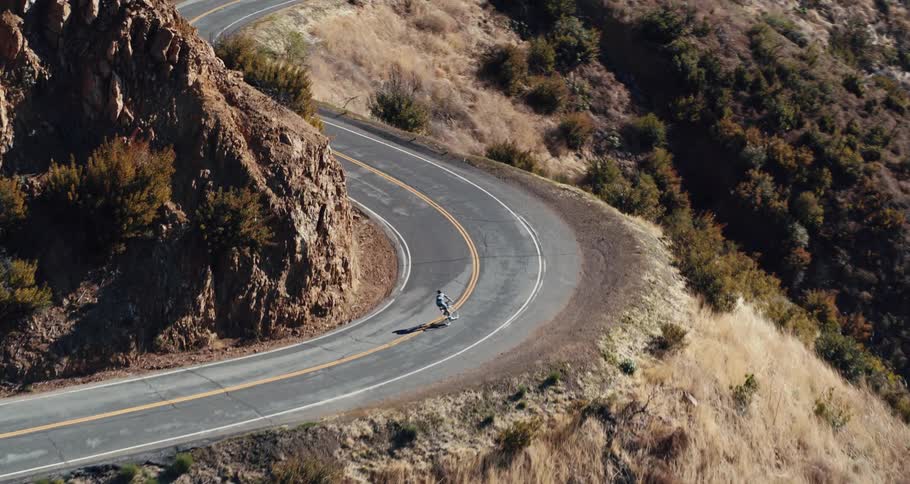 A cyclist travels along a winding mountain pass during the day