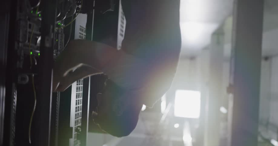 A man in a room working on a server rack with wires and lights