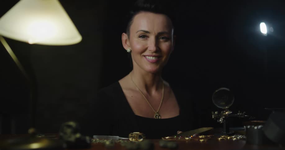 A woman sitting down sorting stops to look up at the camera and smiles