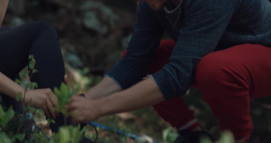 A woman cries as a man examines her hurt foot as they are out hiking