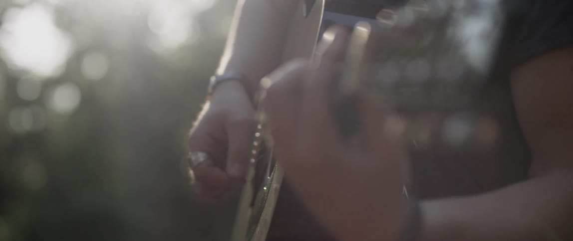 A person plays guitar during the day