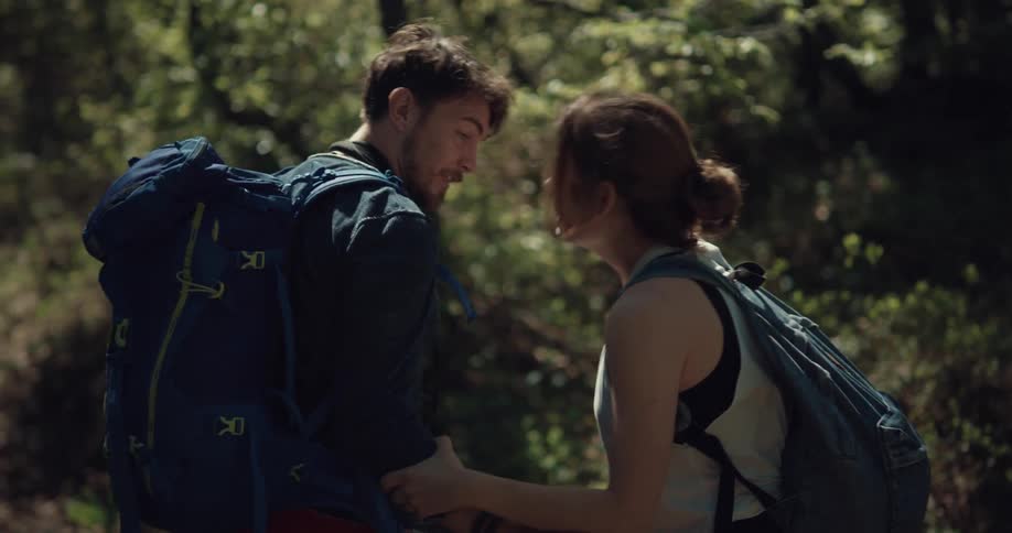 A man kisses his girlfriend on the forehead and continues to help her walk the trail on an injured ankle