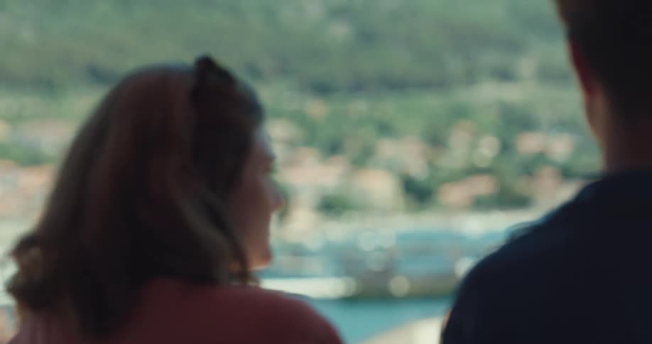 A man and a woman standing with a bay boats and ships in the background
