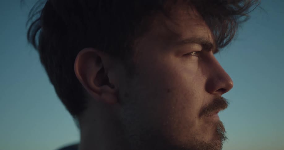 Face of a young man looking at the horizon at sunset