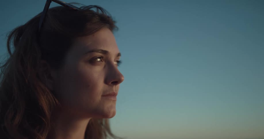 A woman looks off into the distance before turning to the camera and smiling