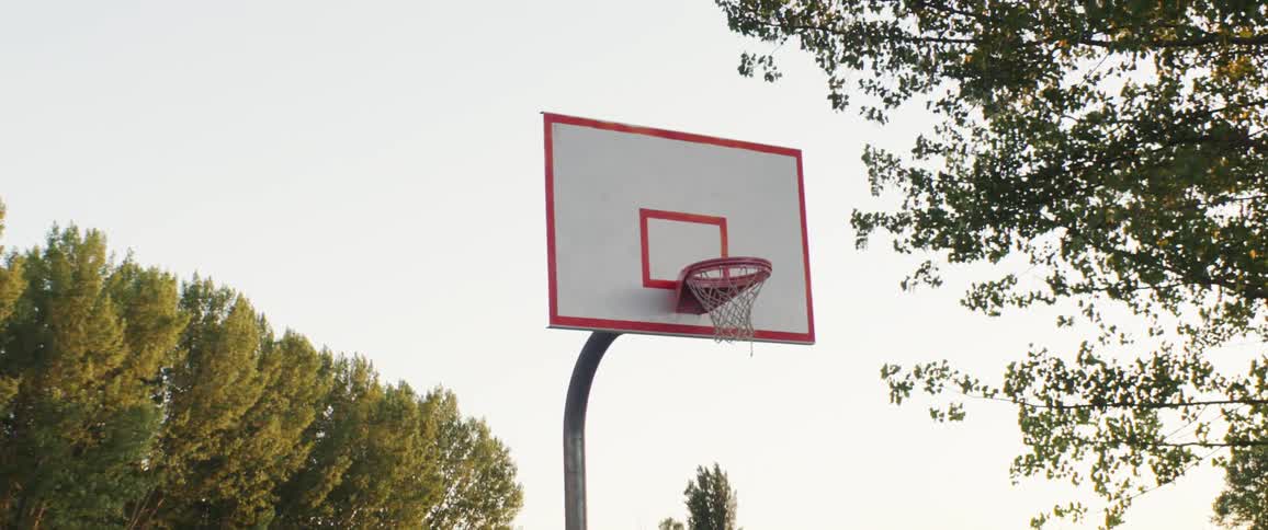 A basketball hoop on an outdoor court in summer