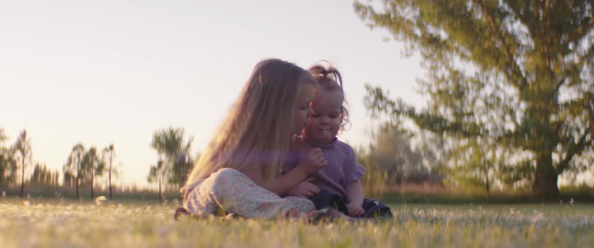 Two sisters playing with flowers outdoors