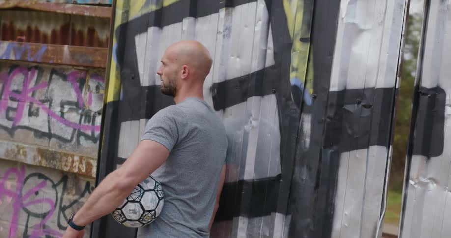 A man standing outside holding a soccer ball