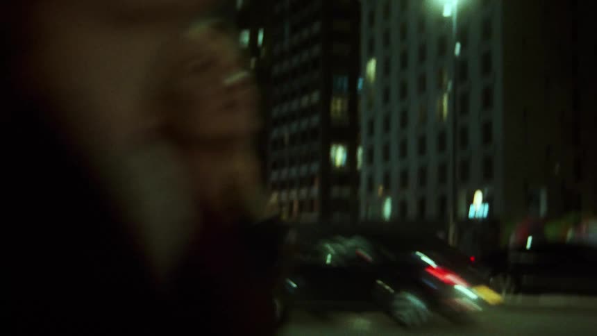 Girlfriends laugh and hug as they run down the city sidewalk looking at the lights and buildings