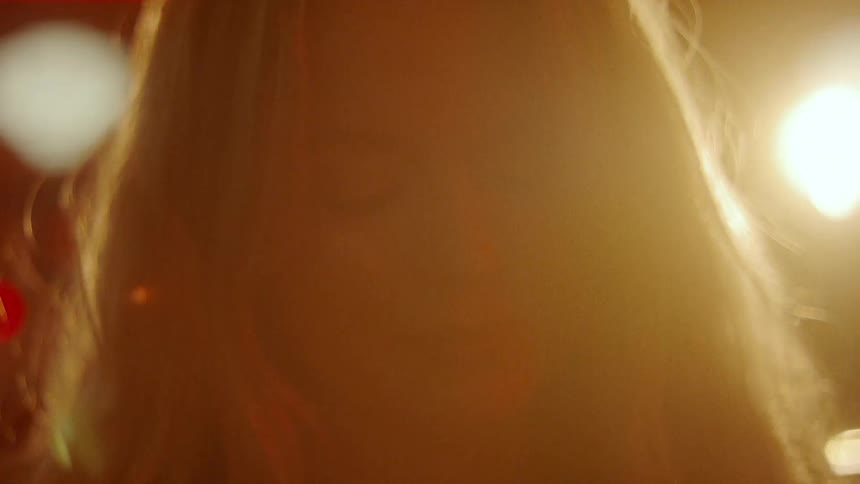 A woman in a nightclub with lights and a wall in the background