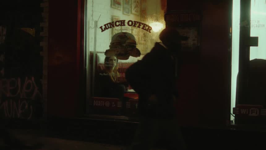 A woman sitting in a restaurant on the street at night