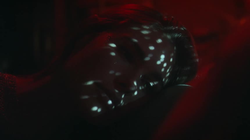 A woman laying down in a nightclub with light shining on her face