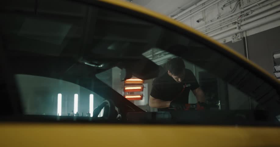 Man uses power tool attachment on car in garage