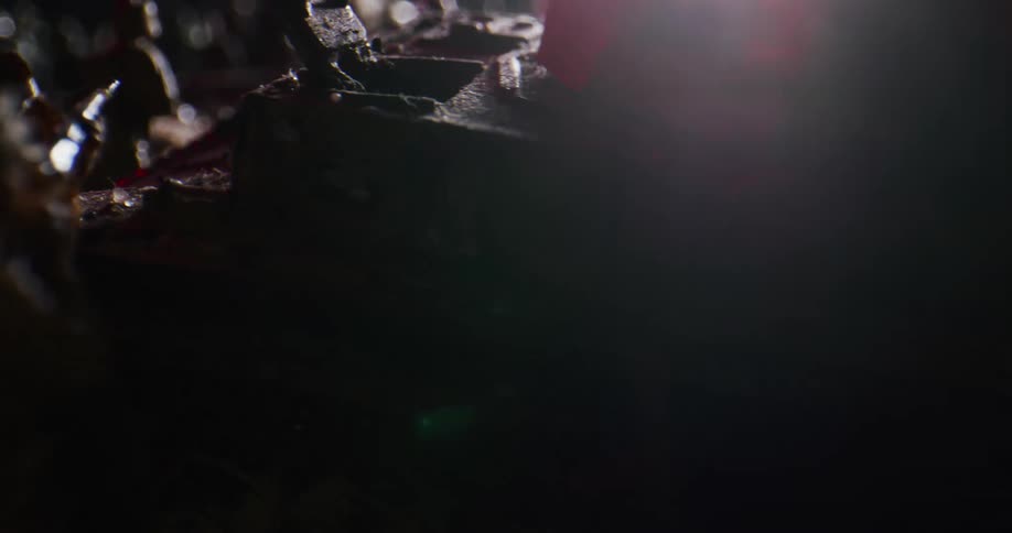 Light passes over shadowy diorama composed of soldier miniatures and army vehicle figurines crowding together
