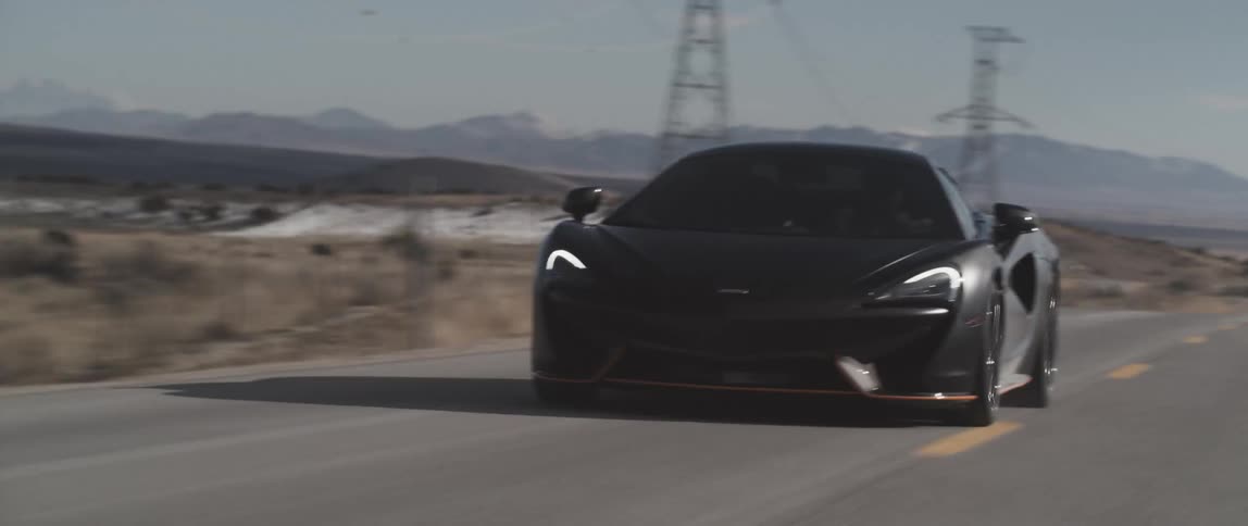 A sports car travels down a country road during the day