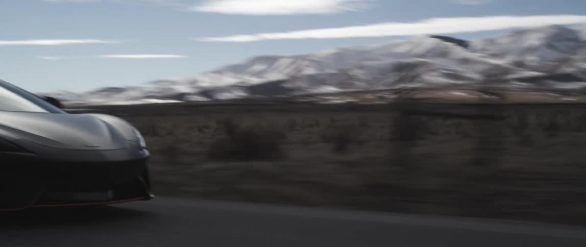 A sports car travels down a countryside road on a clear day