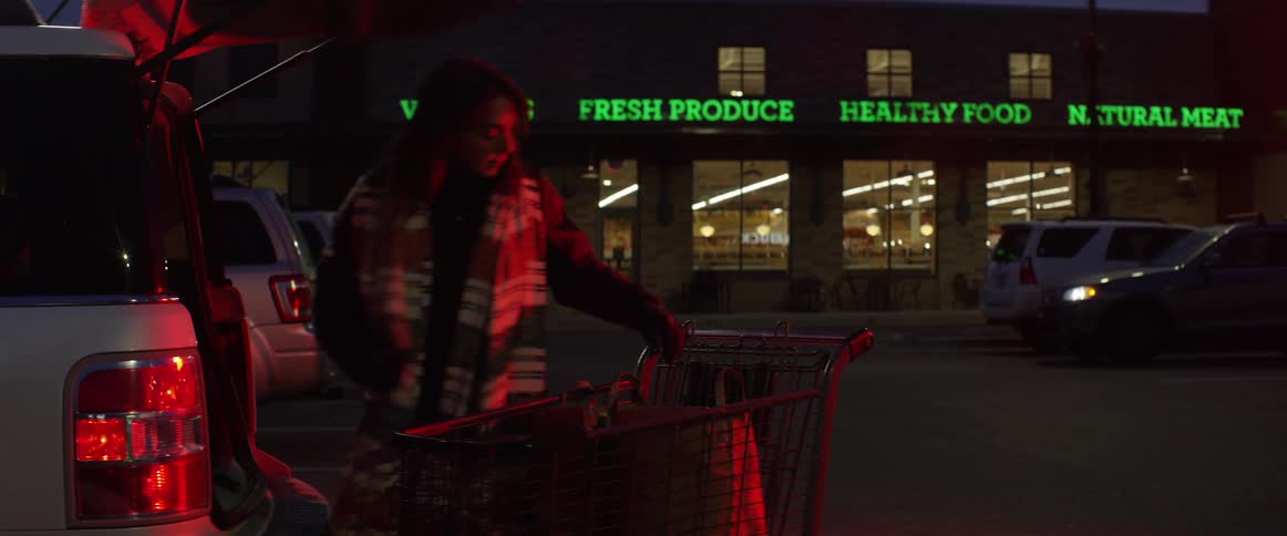 Woman puts groceries from the shopping cart into the back of her car